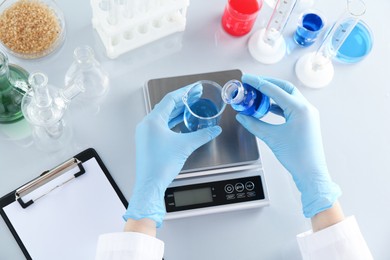 Photo of Scientist working with samples and scales at white mirror table, top view