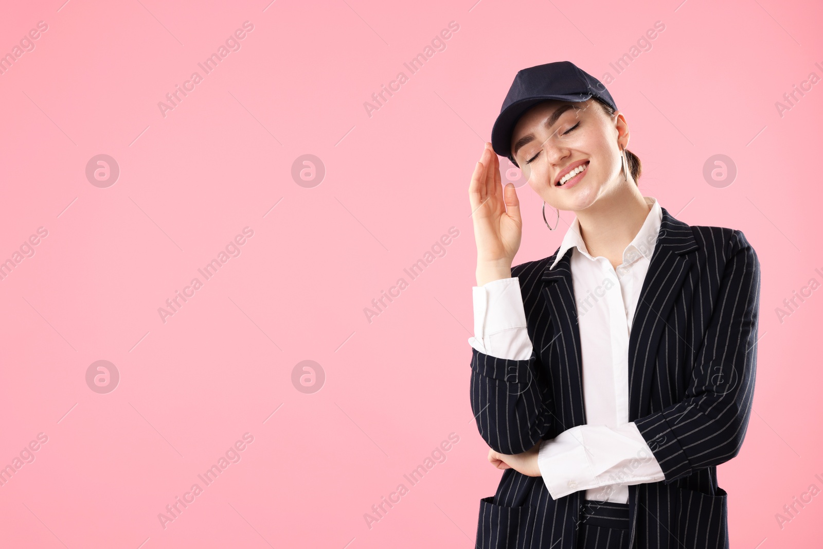 Smiling woman in stylish baseball hat on pink background. Space for text Photo of Smiling woman in stylish baseball hat on pink background. Space for text