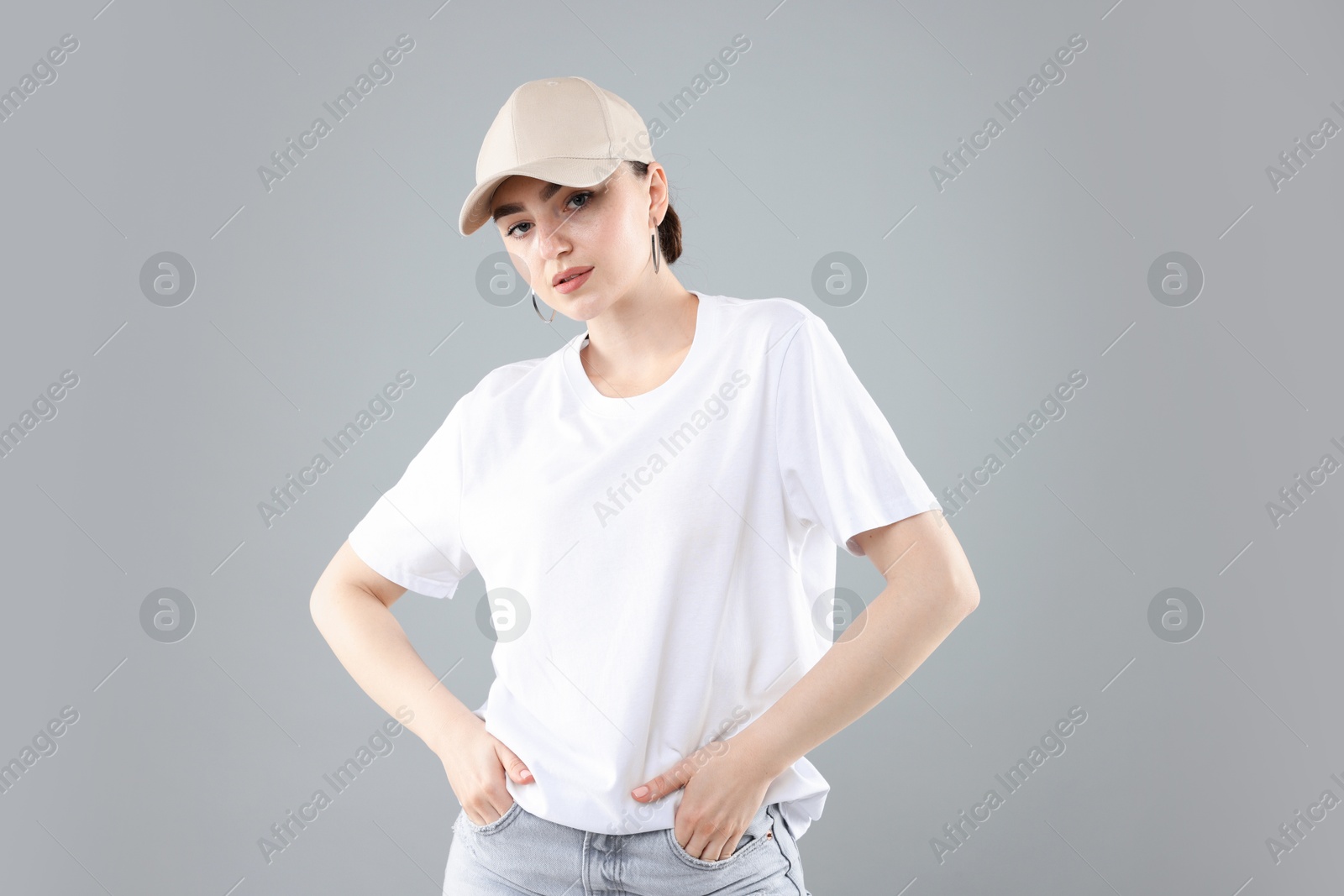 Beautiful woman in stylish baseball hat on grey background Photo of Beautiful woman in stylish baseball hat on grey background