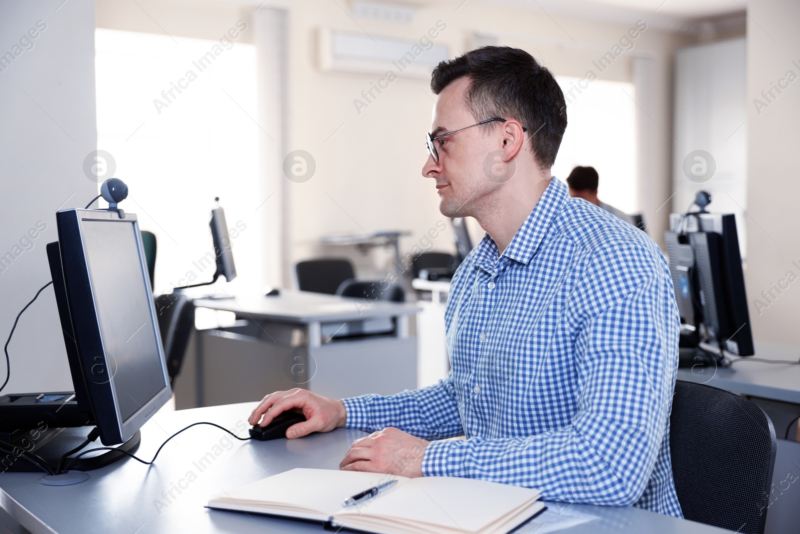 Photo of Man working on computer at desk in public library