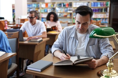 Photo of People studying at desks in public library, selective focus