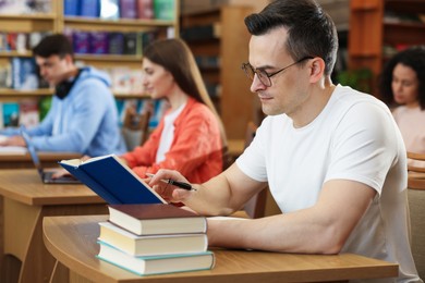 Photo of People studying at desks in public library, selective focus