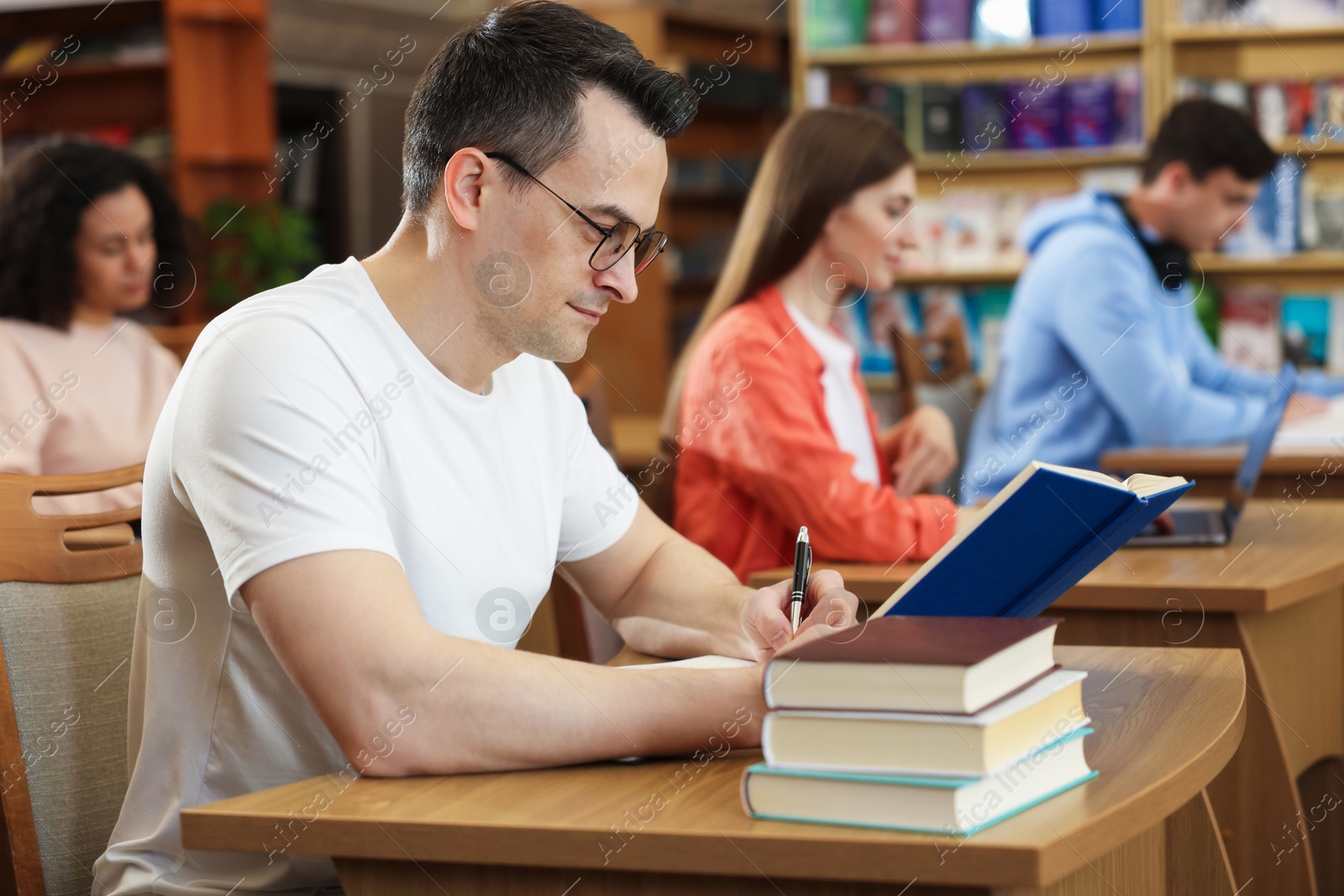 People studying at desks in public library, selective focus Photo of People studying at desks in public library, selective focus
