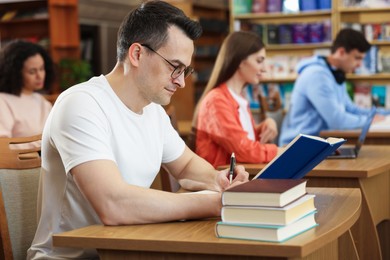 Photo of People studying at desks in public library, selective focus