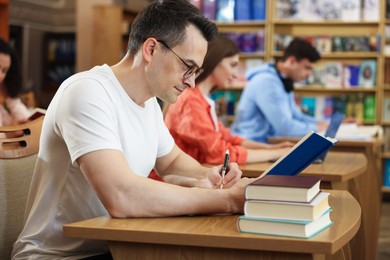 Photo of People studying at desks in public library, selective focus