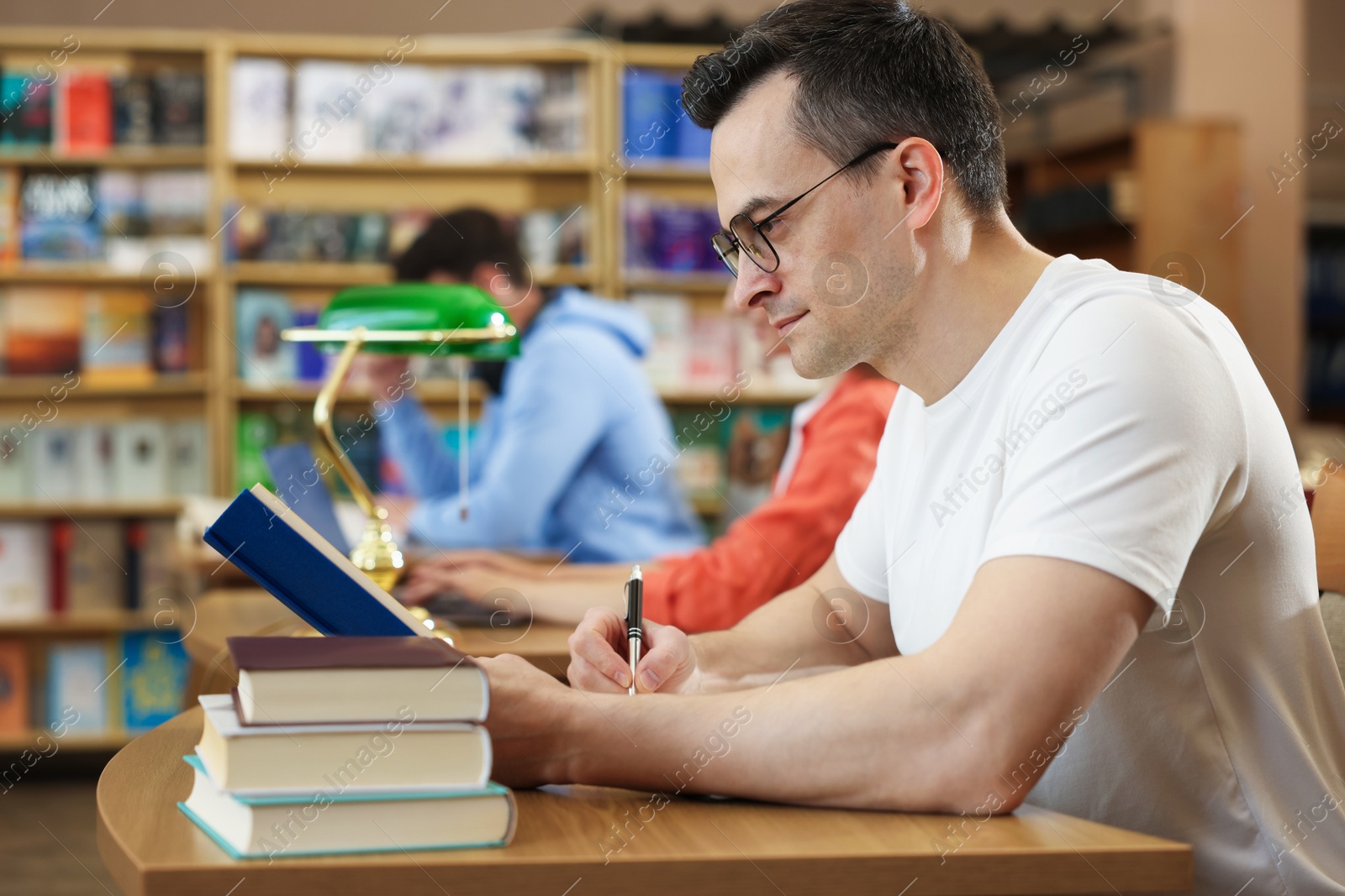 People studying at desks in public library, selective focus Photo of People studying at desks in public library, selective focus