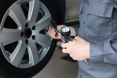 Photo of Mechanic inflating new tire at car service, closeup