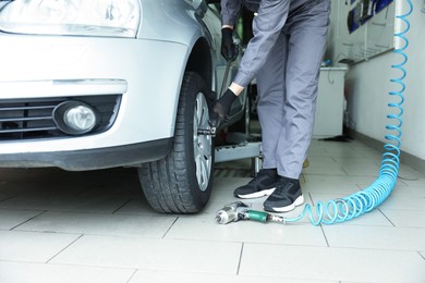 Photo of Mechanic changing tire at car service, closeup