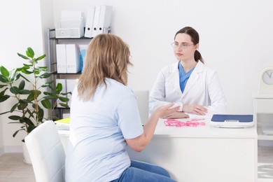 Photo of Weight loss. Nutritionist consulting overweight woman at white desk in clinic