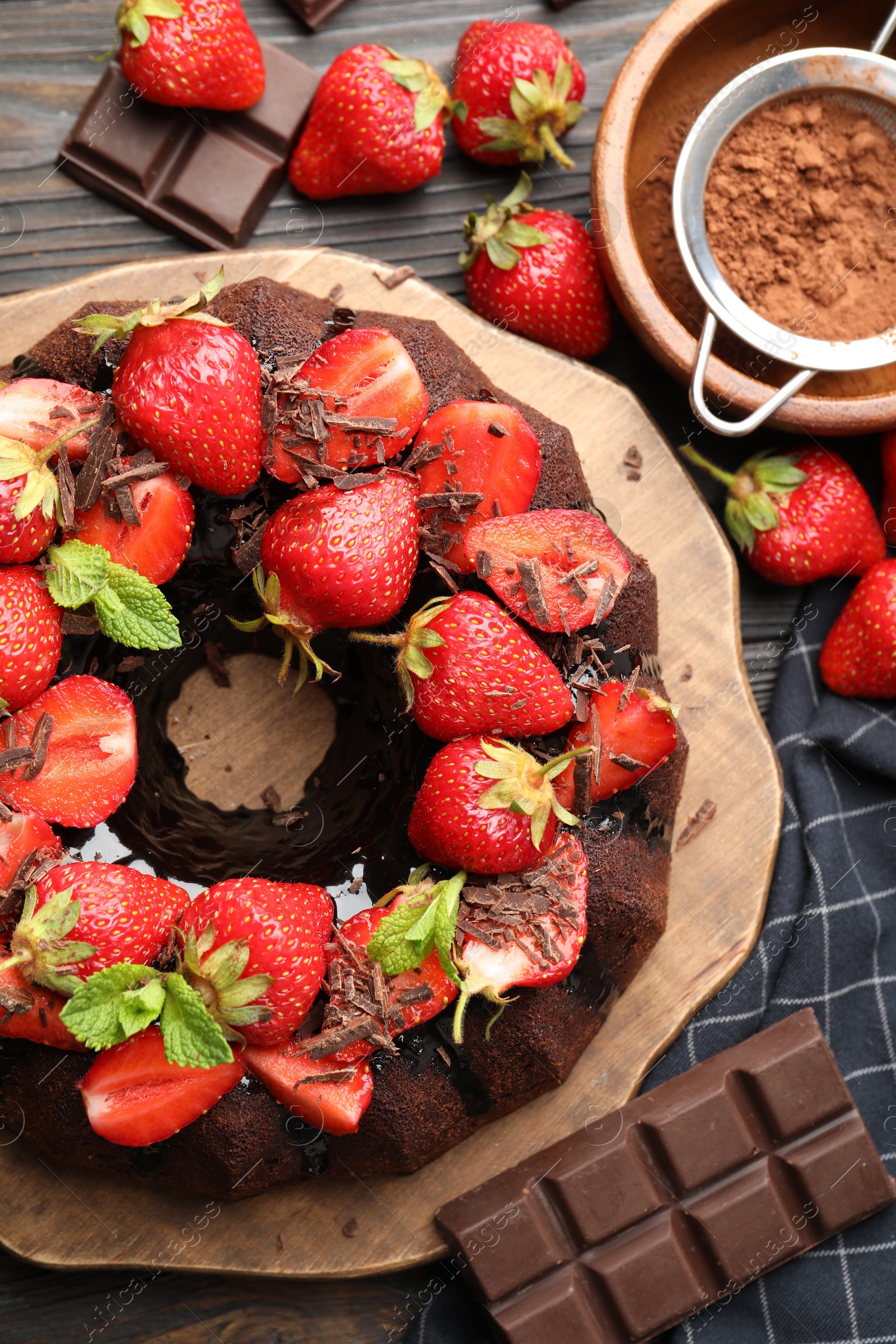 Delicious bundt cake with strawberries, mint and chocolate shavings on wooden table, flat lay Photo of Delicious bundt cake with strawberries, mint and chocolate shavings on wooden table, flat lay
