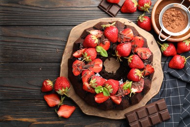 Photo of Delicious bundt cake with strawberries, mint and chocolate shavings on wooden table, flat lay