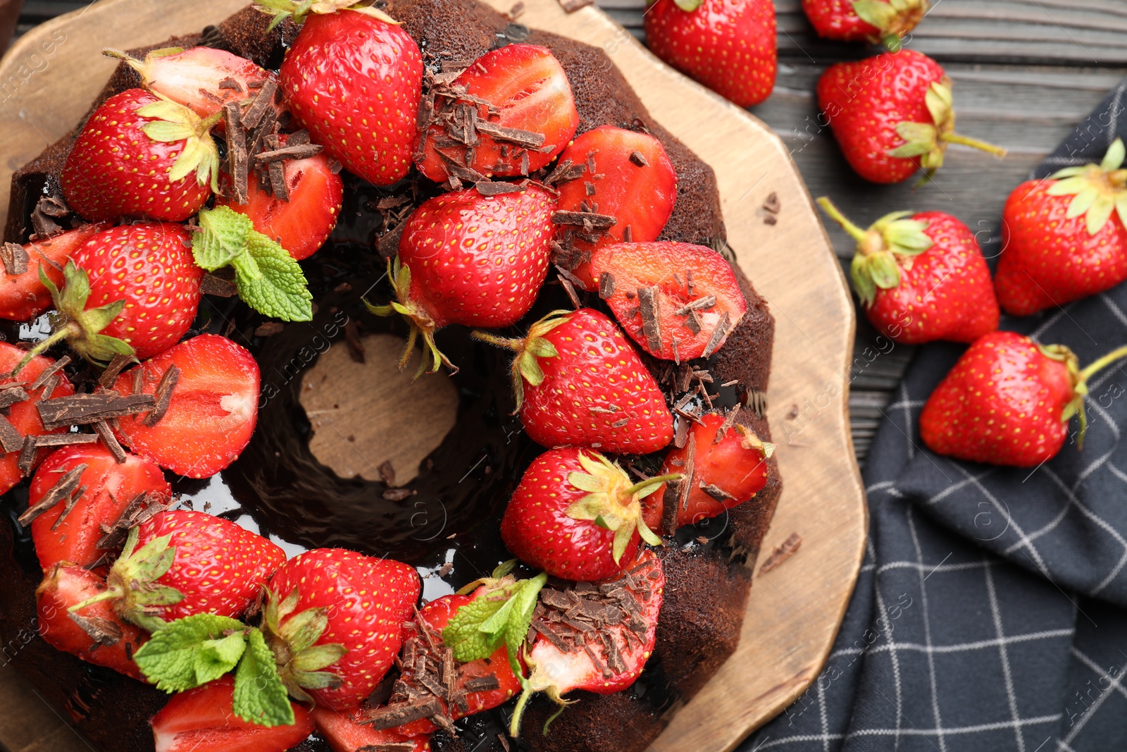 Delicious bundt cake with strawberries, mint and chocolate shavings on wooden table, flat lay Photo of Delicious bundt cake with strawberries, mint and chocolate shavings on wooden table, flat lay