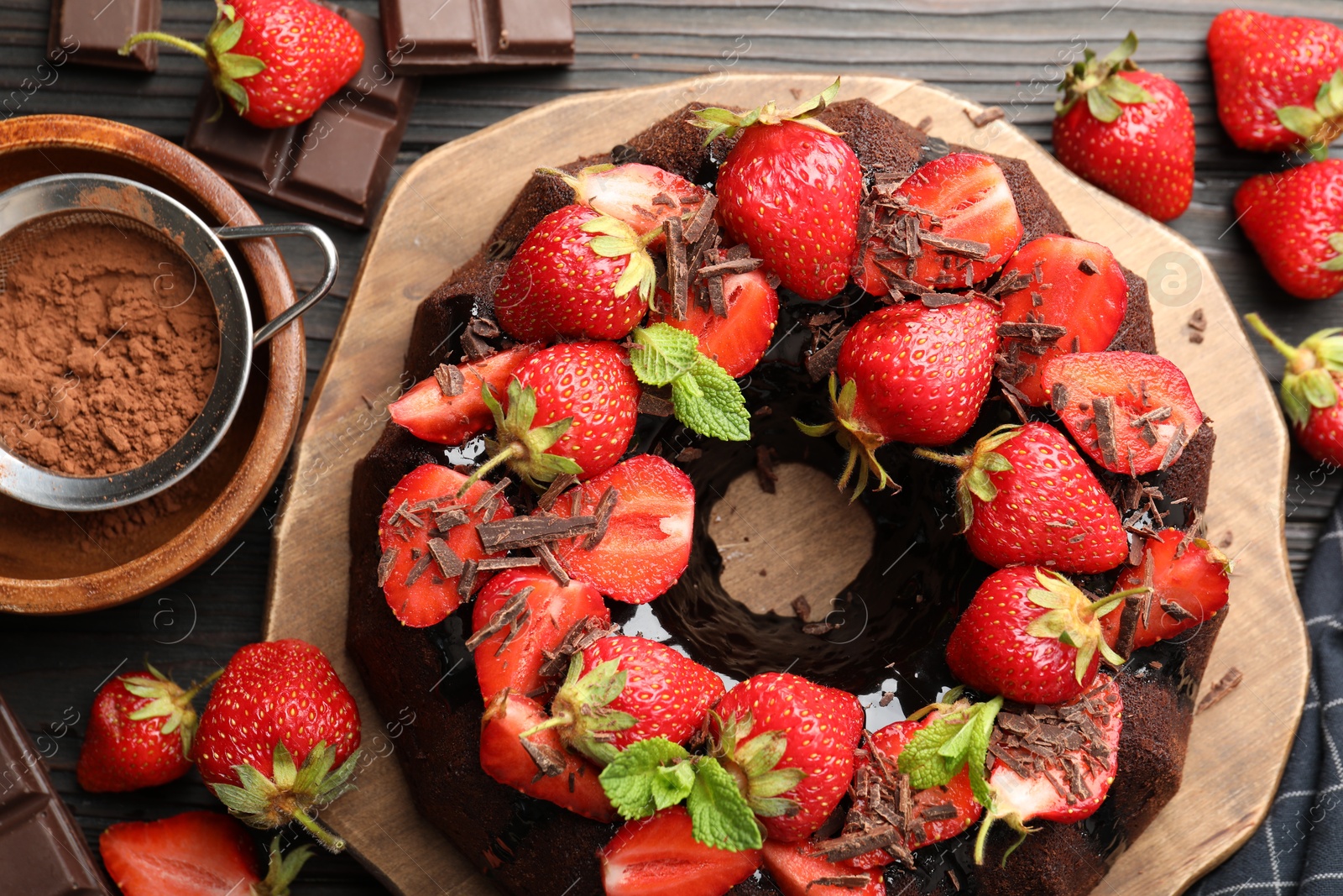 Delicious bundt cake with strawberries, mint and chocolate shavings on wooden table, flat lay Photo of Delicious bundt cake with strawberries, mint and chocolate shavings on wooden table, flat lay