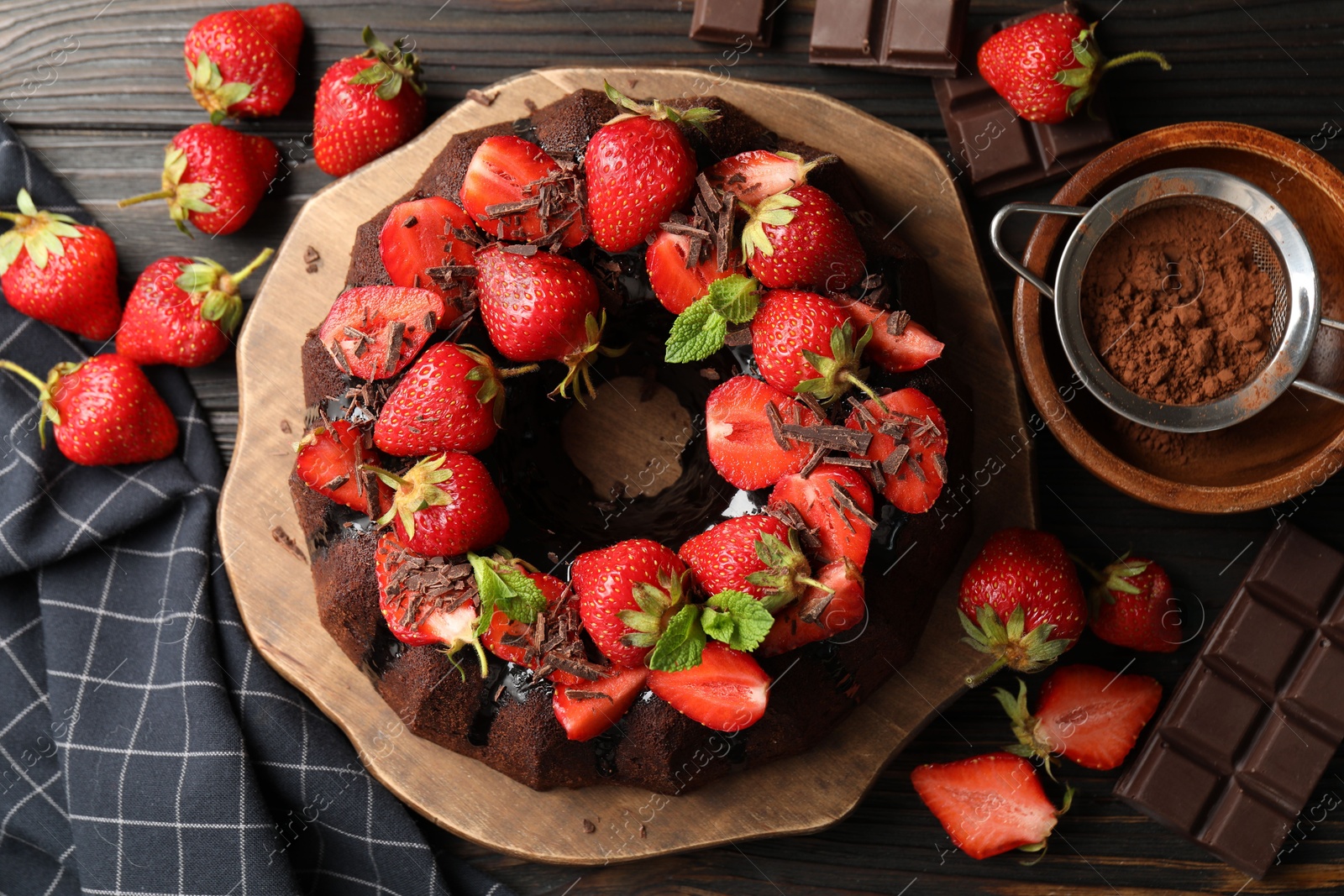 Delicious bundt cake with strawberries, mint and chocolate shavings on wooden table, flat lay Photo of Delicious bundt cake with strawberries, mint and chocolate shavings on wooden table, flat lay