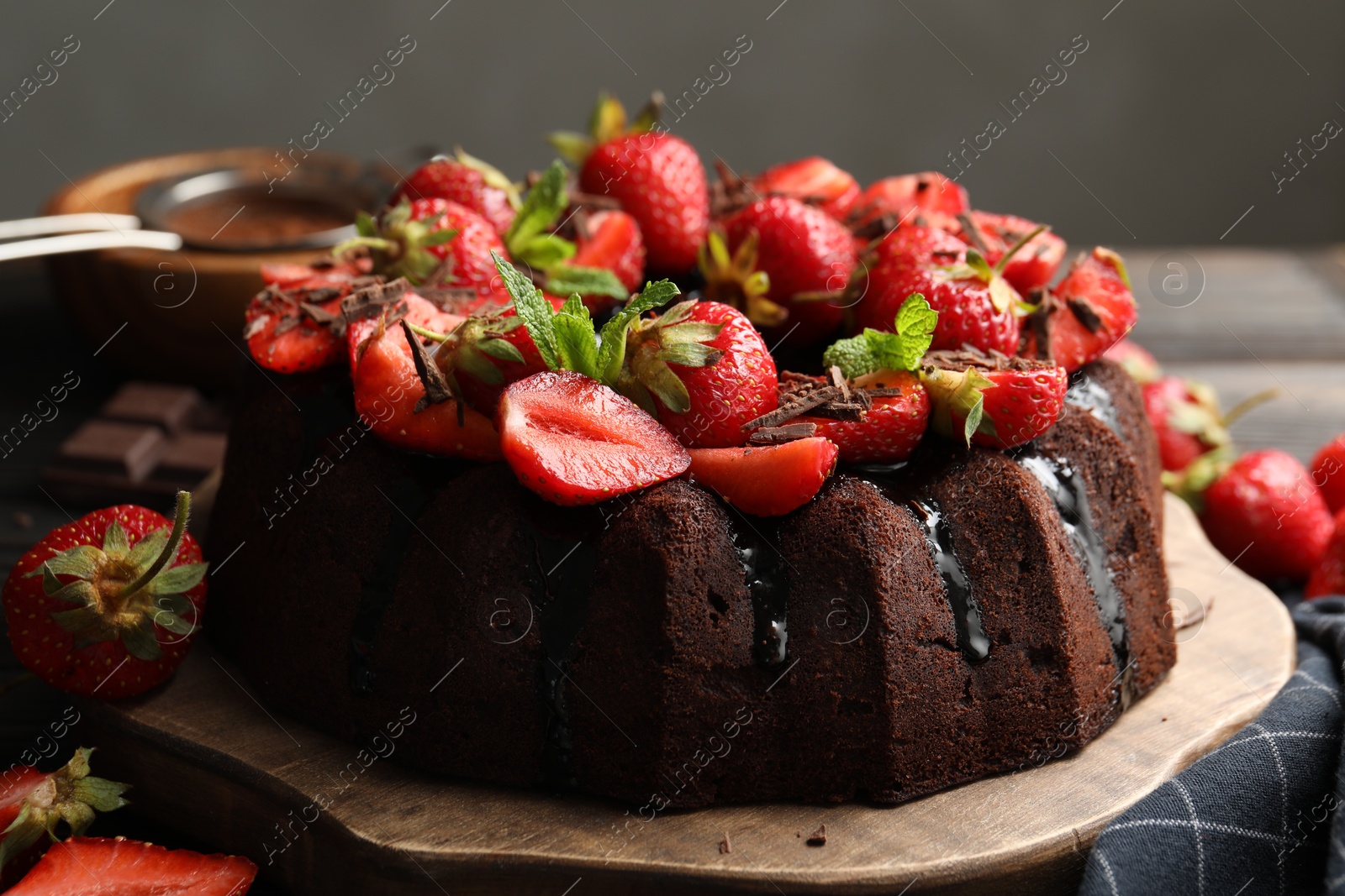Delicious bundt cake with strawberries, mint and chocolate shavings on table against grey background, closeup Photo of Delicious bundt cake with strawberries, mint and chocolate shavings on table against grey background, closeup