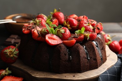 Photo of Delicious bundt cake with strawberries, mint and chocolate shavings on table against grey background, closeup