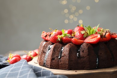 Photo of Delicious chocolate bundt cake with strawberries and mint on table against grey background, closeup