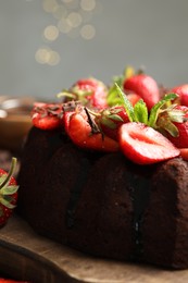 Photo of Delicious chocolate bundt cake with strawberries and mint on table against grey background, closeup