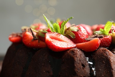 Photo of Delicious chocolate bundt cake with strawberries and mint on grey background, closeup