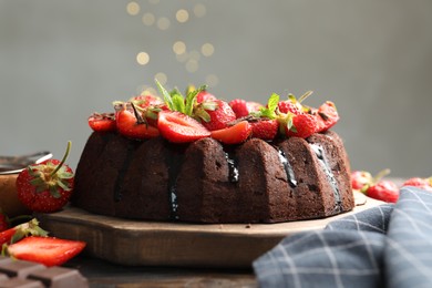 Photo of Delicious chocolate bundt cake with strawberries and mint on table against grey background, closeup