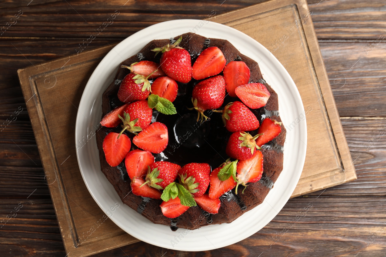 Delicious chocolate bundt cake with strawberries and mint on wooden table, top view Photo of Delicious chocolate bundt cake with strawberries and mint on wooden table, top view