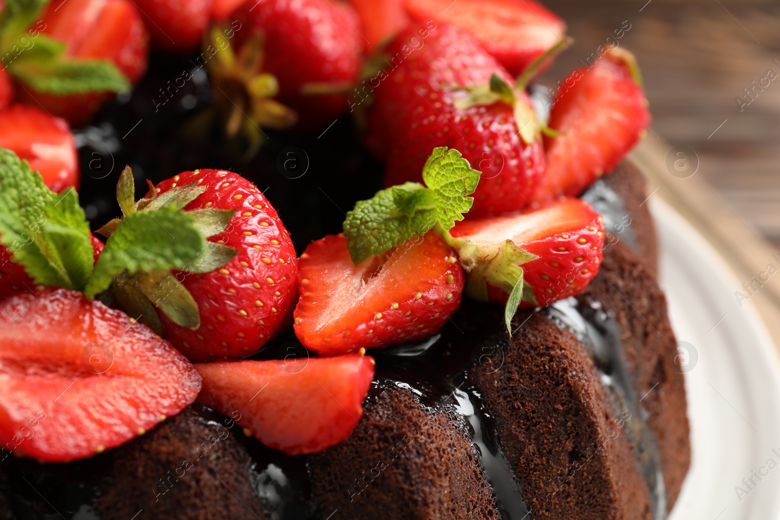 Delicious chocolate bundt cake with strawberries and mint on table, closeup Photo of Delicious chocolate bundt cake with strawberries and mint on table, closeup