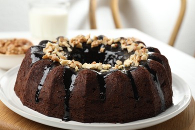 Photo of Delicious chocolate bundt cake with nuts on table indoors, closeup