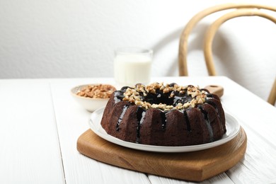 Photo of Delicious chocolate bundt cake with nuts on white wooden table indoors