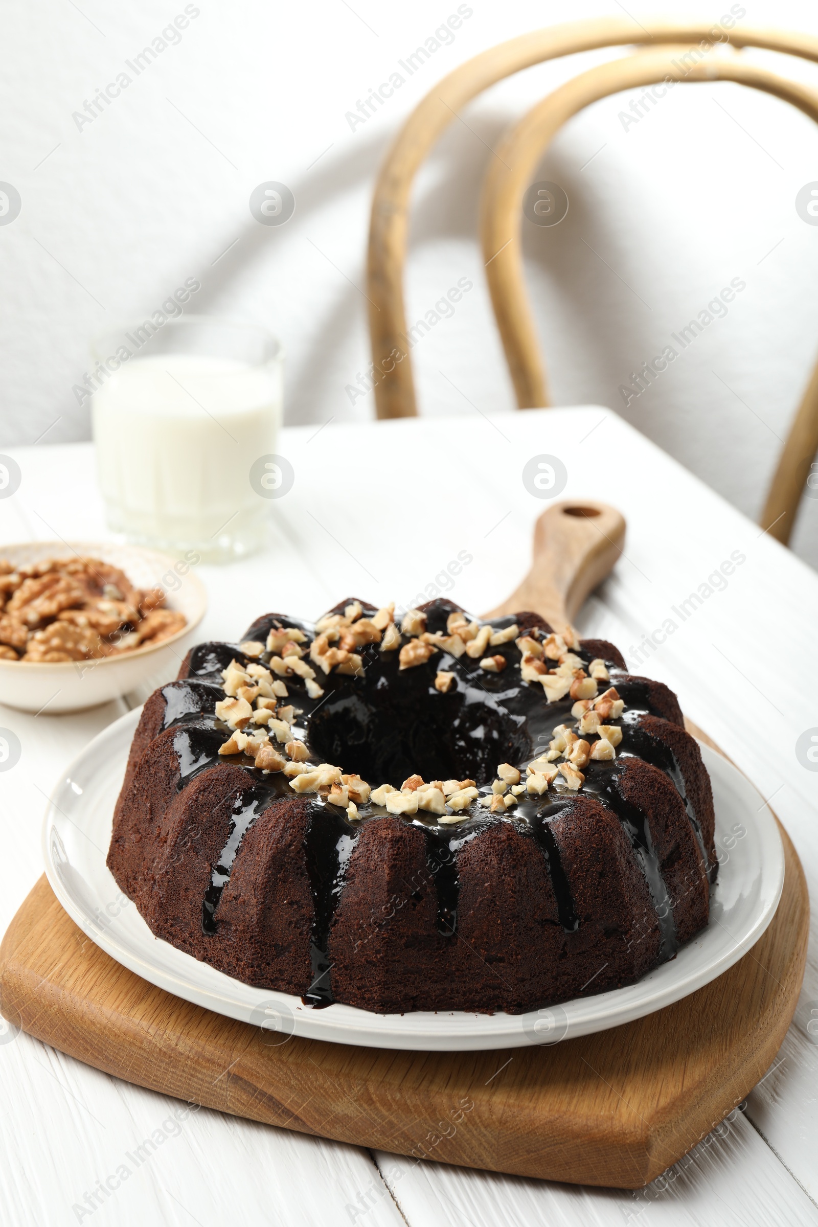 Delicious chocolate bundt cake with nuts on white wooden table indoors Photo of Delicious chocolate bundt cake with nuts on white wooden table indoors