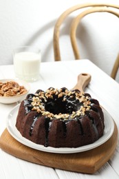 Photo of Delicious chocolate bundt cake with nuts on white wooden table indoors