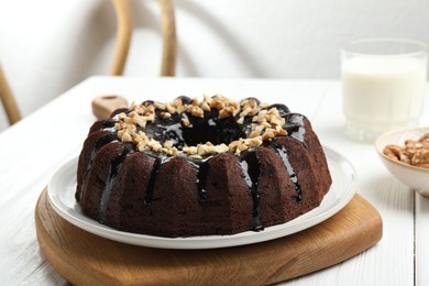 Photo of Delicious chocolate bundt cake with nuts on white wooden table indoors, closeup