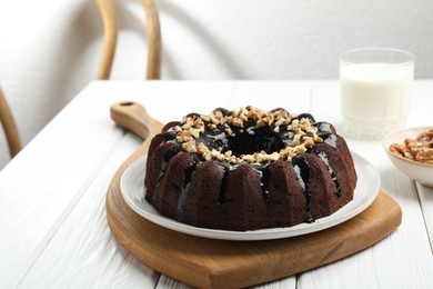 Photo of Delicious chocolate bundt cake with nuts on white wooden table indoors, closeup