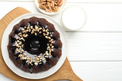 Photo of Delicious chocolate bundt cake with nuts and glass of milk on white wooden table, flat lay. Space for text