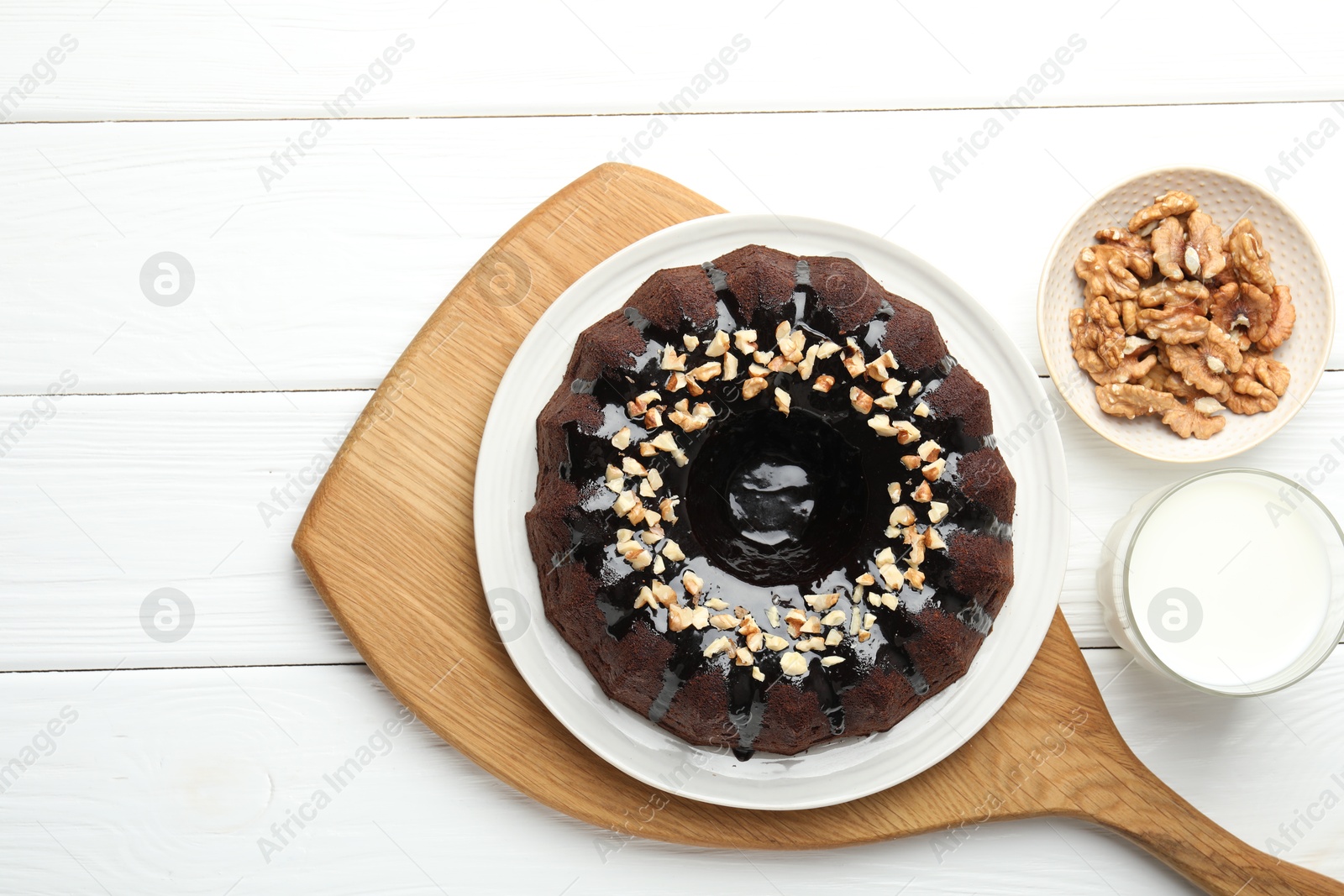 Delicious chocolate bundt cake with nuts and glass of milk on white wooden table, flat lay Photo of Delicious chocolate bundt cake with nuts and glass of milk on white wooden table, flat lay