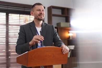 Photo of Man giving public speech with microphone at lectern indoors