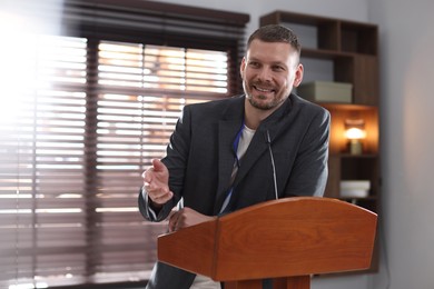 Photo of Man giving public speech with microphone at lectern indoors