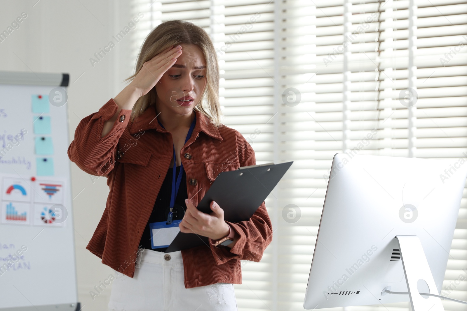Photo of Fear of public speaking. Nervous woman with clipboard indoors