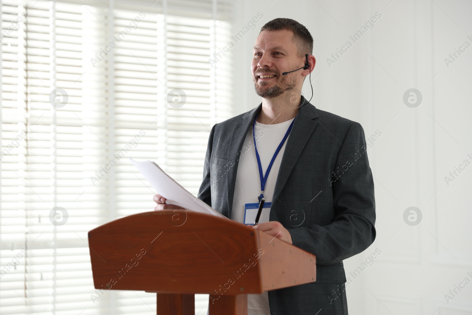 Man giving public speech with microphone at lectern indoors Photo of Man giving public speech with microphone at lectern indoors