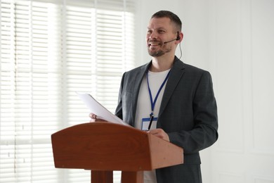 Photo of Man giving public speech with microphone at lectern indoors