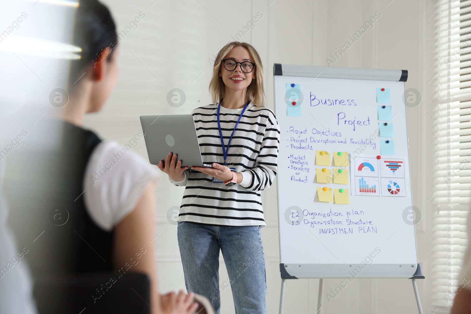 Woman giving public speech near whiteboard in front of audience indoors Photo of Woman giving public speech near whiteboard in front of audience indoors