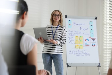 Photo of Woman giving public speech near whiteboard in front of audience indoors