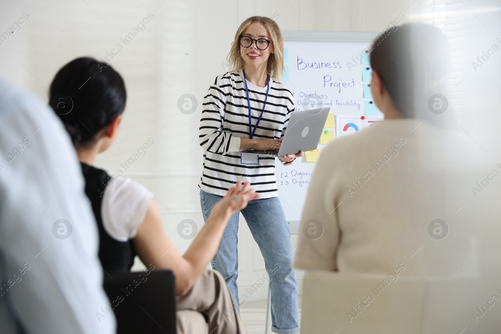 Woman giving public speech near whiteboard in front of audience indoors Photo of Woman giving public speech near whiteboard in front of audience indoors