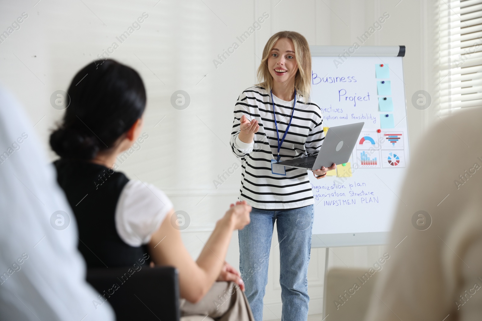 Woman giving public speech near whiteboard in front of audience indoors Photo of Woman giving public speech near whiteboard in front of audience indoors