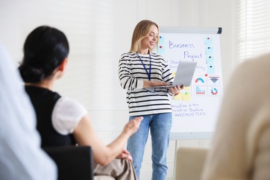 Photo of Woman giving public speech near whiteboard in front of audience indoors