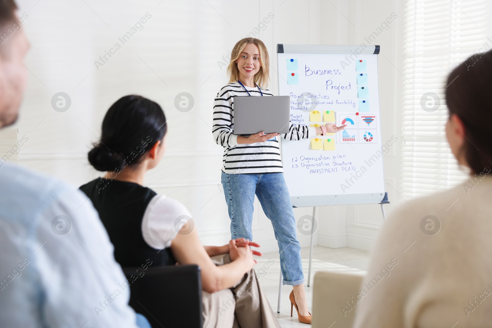 Woman giving public speech near whiteboard in front of audience indoors Photo of Woman giving public speech near whiteboard in front of audience indoors