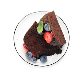 Photo of Pieces of delicious chocolate bundt cake with strawberries and blueberries isolated on white, top view