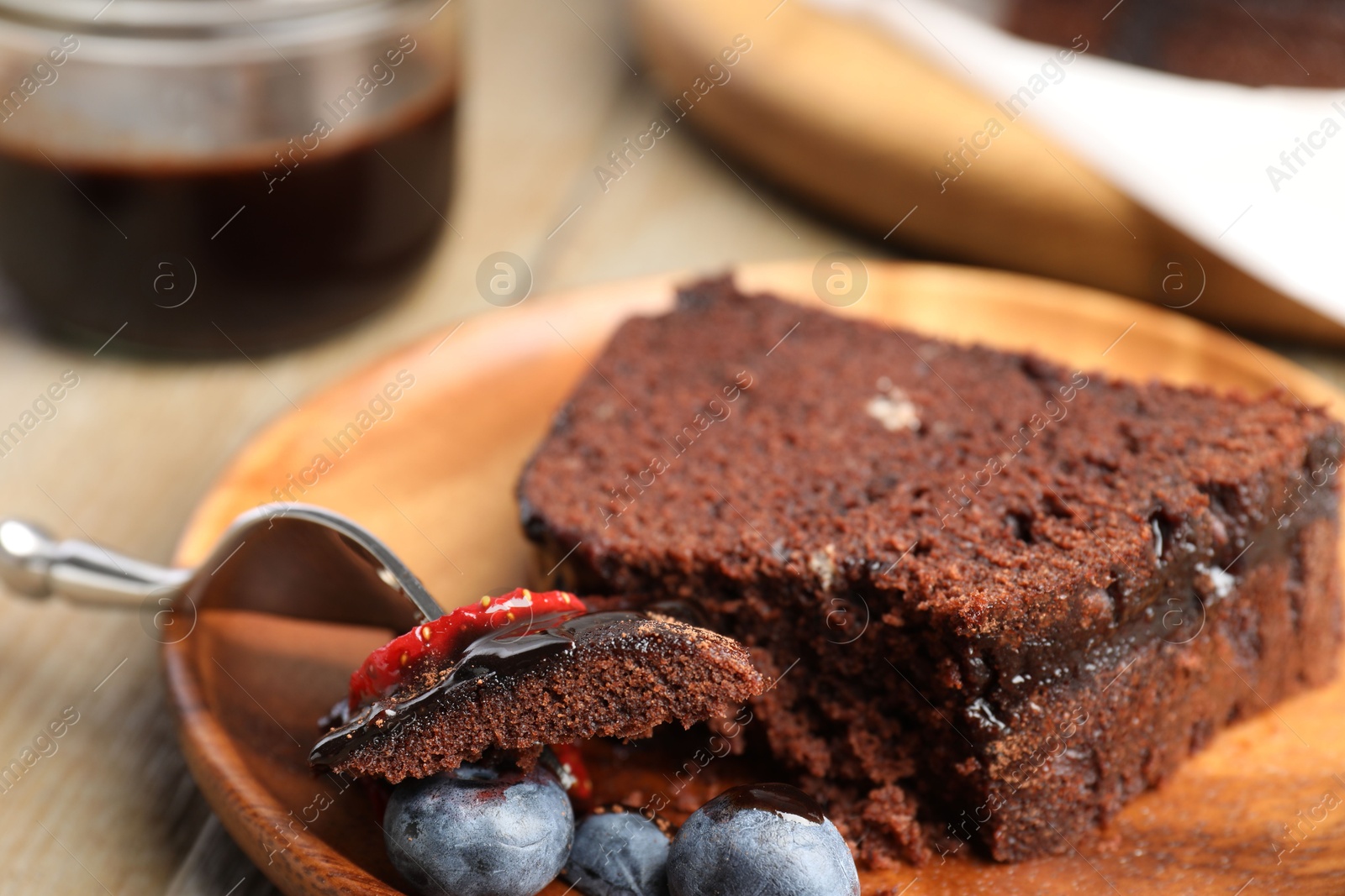 Piece of delicious chocolate bundt cake with blueberries on wooden table, closeup Photo of Piece of delicious chocolate bundt cake with blueberries on wooden table, closeup