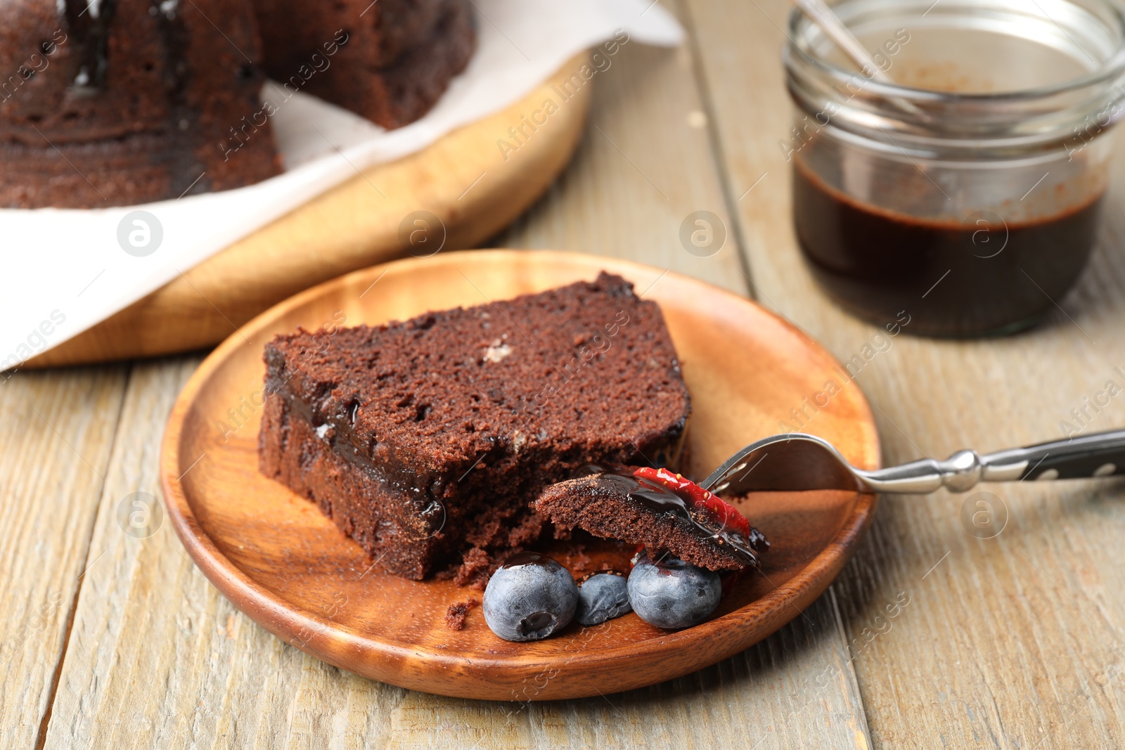 Piece of delicious chocolate bundt cake with blueberries on wooden table, closeup Photo of Piece of delicious chocolate bundt cake with blueberries on wooden table, closeup