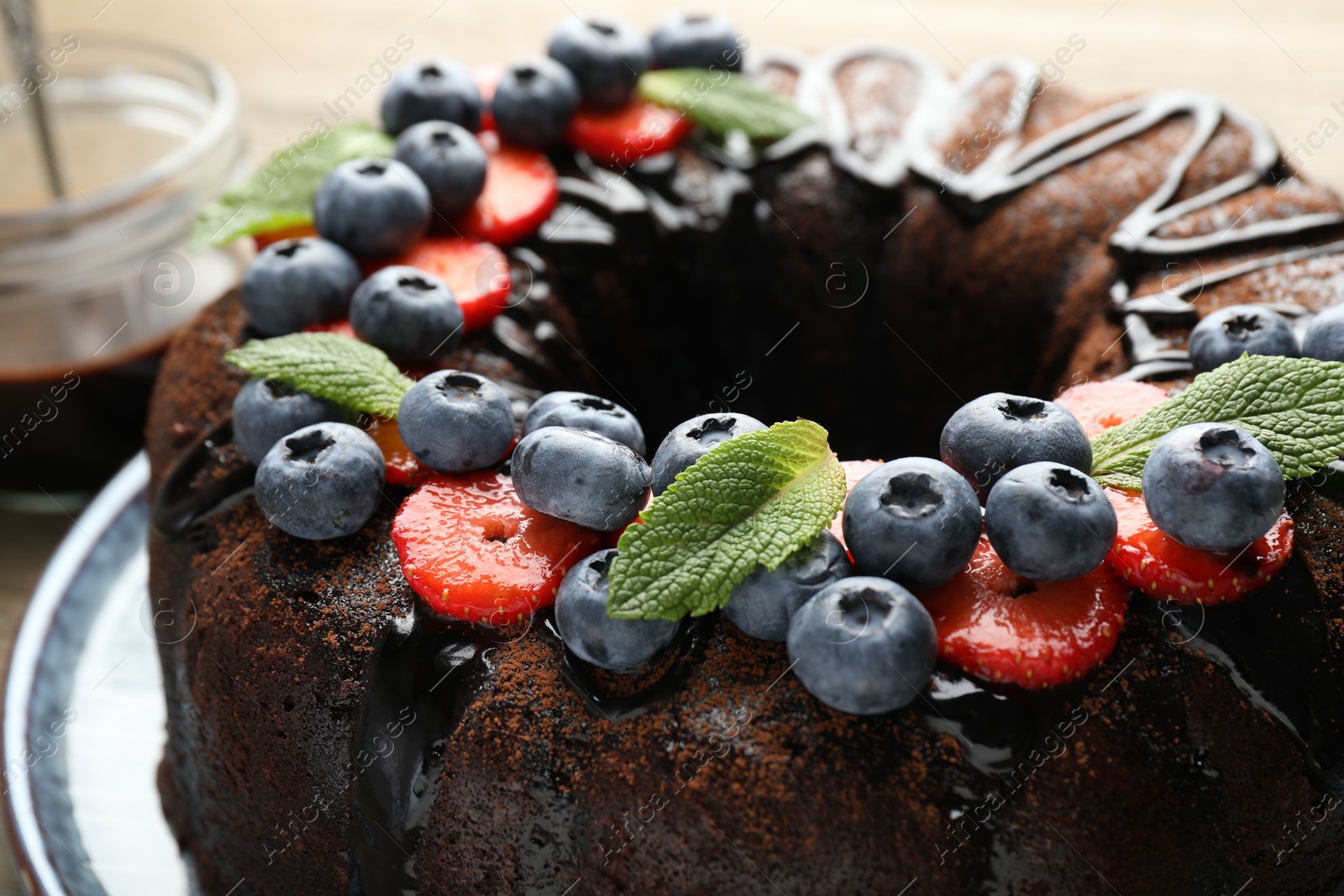 Delicious chocolate bundt cake with strawberries, mint and blueberries on table, closeup Photo of Delicious chocolate bundt cake with strawberries, mint and blueberries on table, closeup