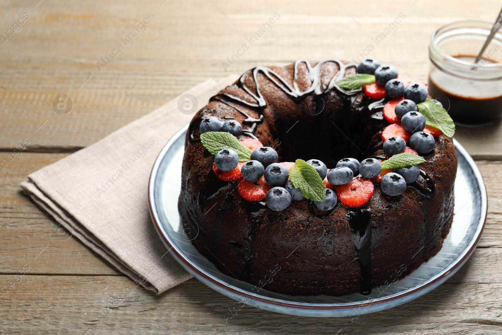 Delicious chocolate bundt cake with strawberries, mint and blueberries on wooden table, closeup Photo of Delicious chocolate bundt cake with strawberries, mint and blueberries on wooden table, closeup
